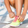 Running shoes - woman tying shoe laces. Closeup of female sport fitness runner getting ready for jogging outdoors on waterfront in late summer or fall